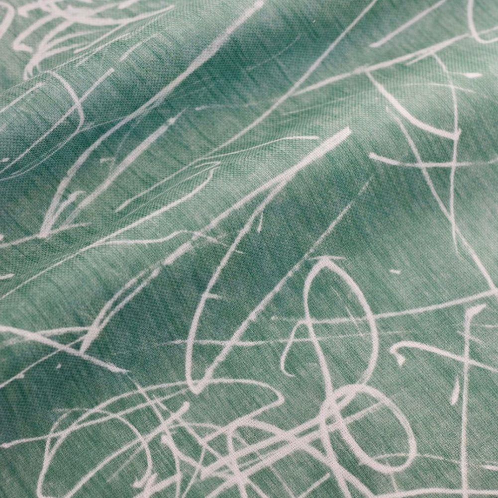 A close-up view of fabric with a green color and a white scribble pattern.
