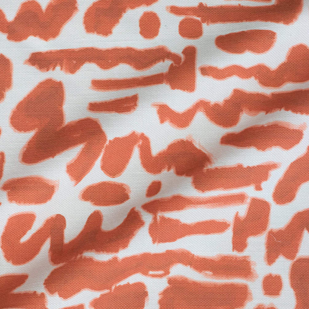 A fabric with a pattern of abstract doodles in orange on a white background.