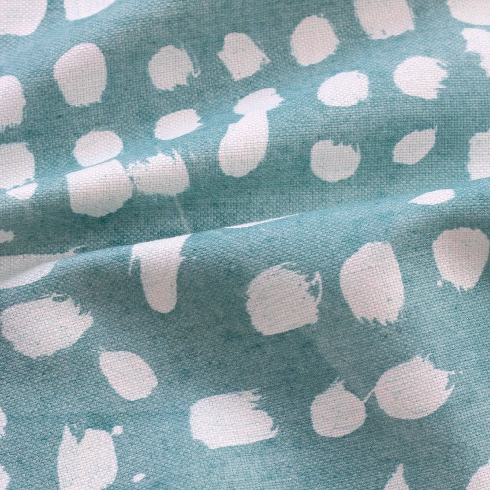 A fabric with a painterly dot design in an organic pattern on a blue background.