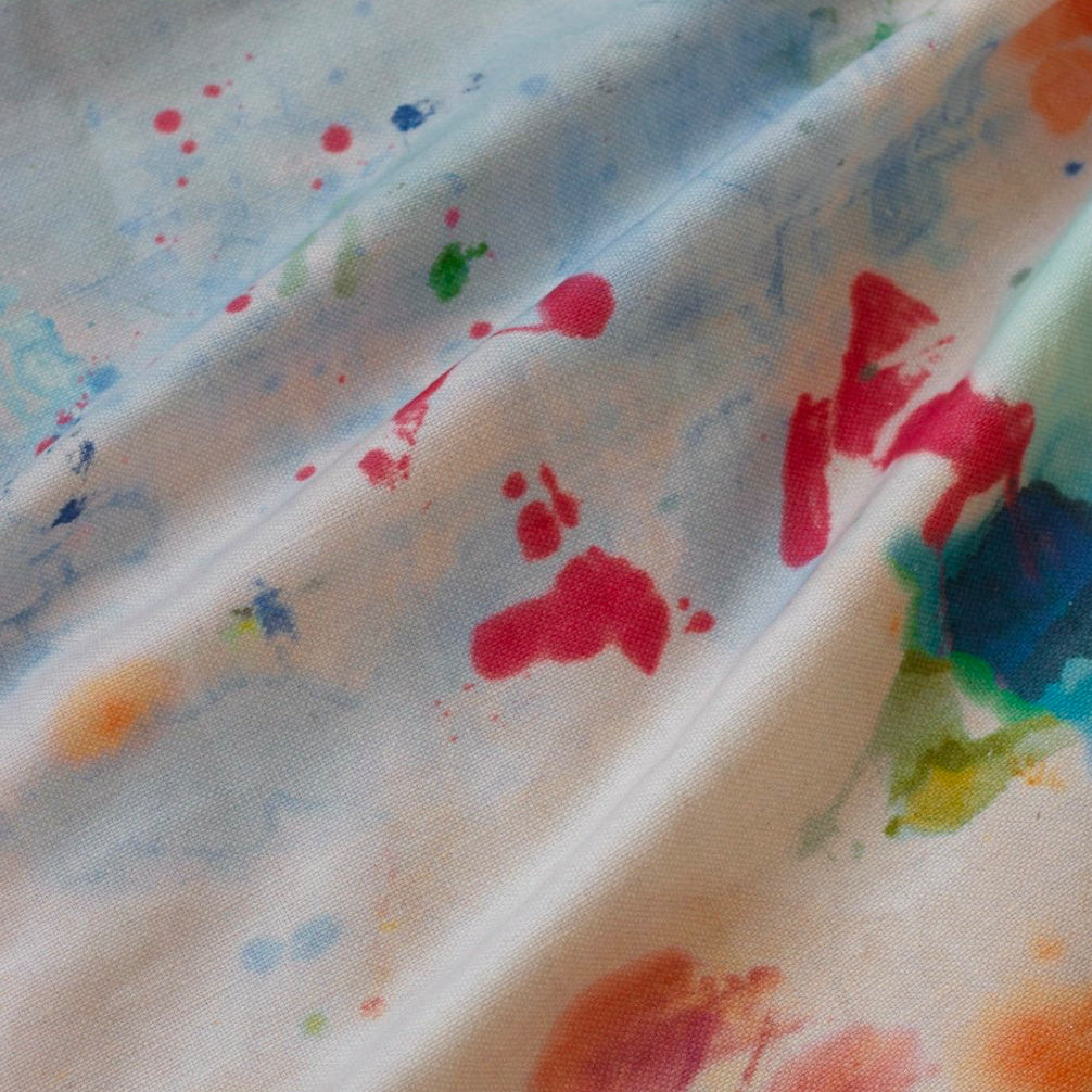 A fabric with a painted splash pattern featuring a variety of colors on a white background.