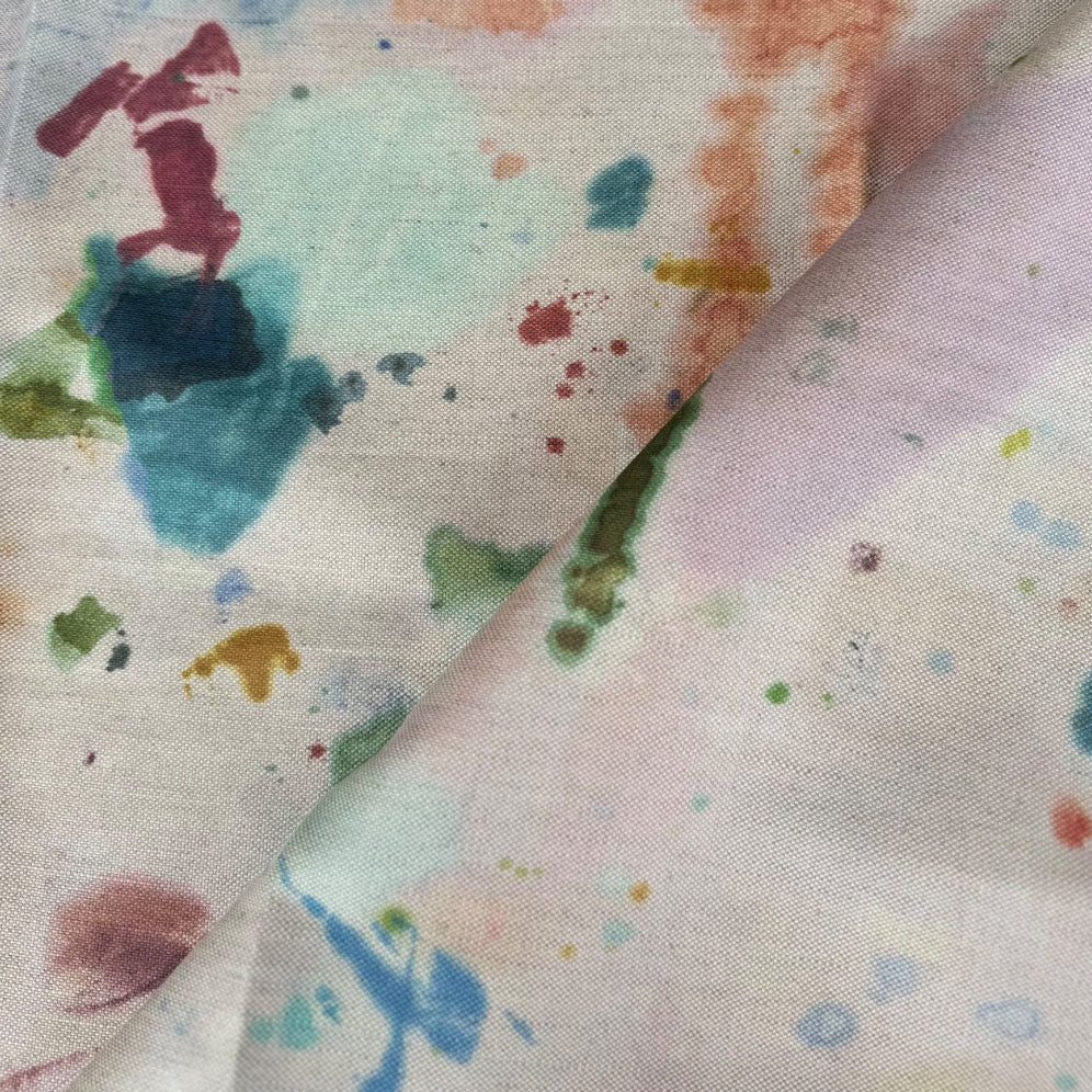A fabric with a midweight cotton linen composition featuring a printed design with various colors including blue, green, and pink resembling a watercolor painting on a light background.