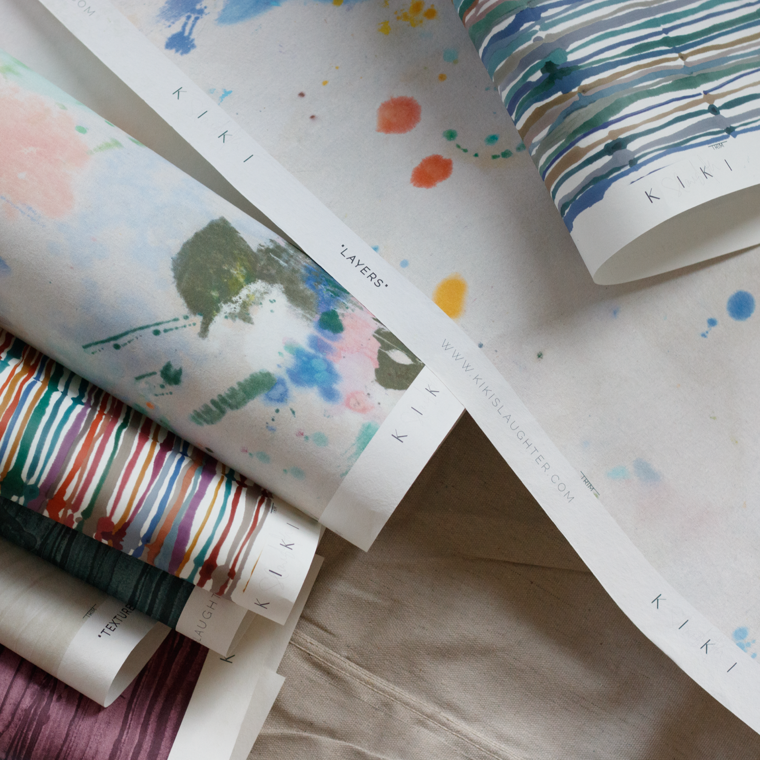 Rolls of colorful paper with various patterns on a textured surface