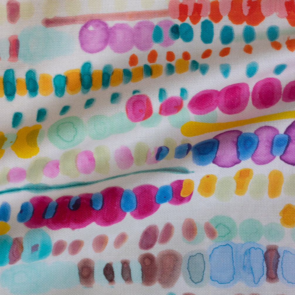 A colorful textile design featuring a close-up of a pattern with numerous abstract, painterly brush strokes in various colors.