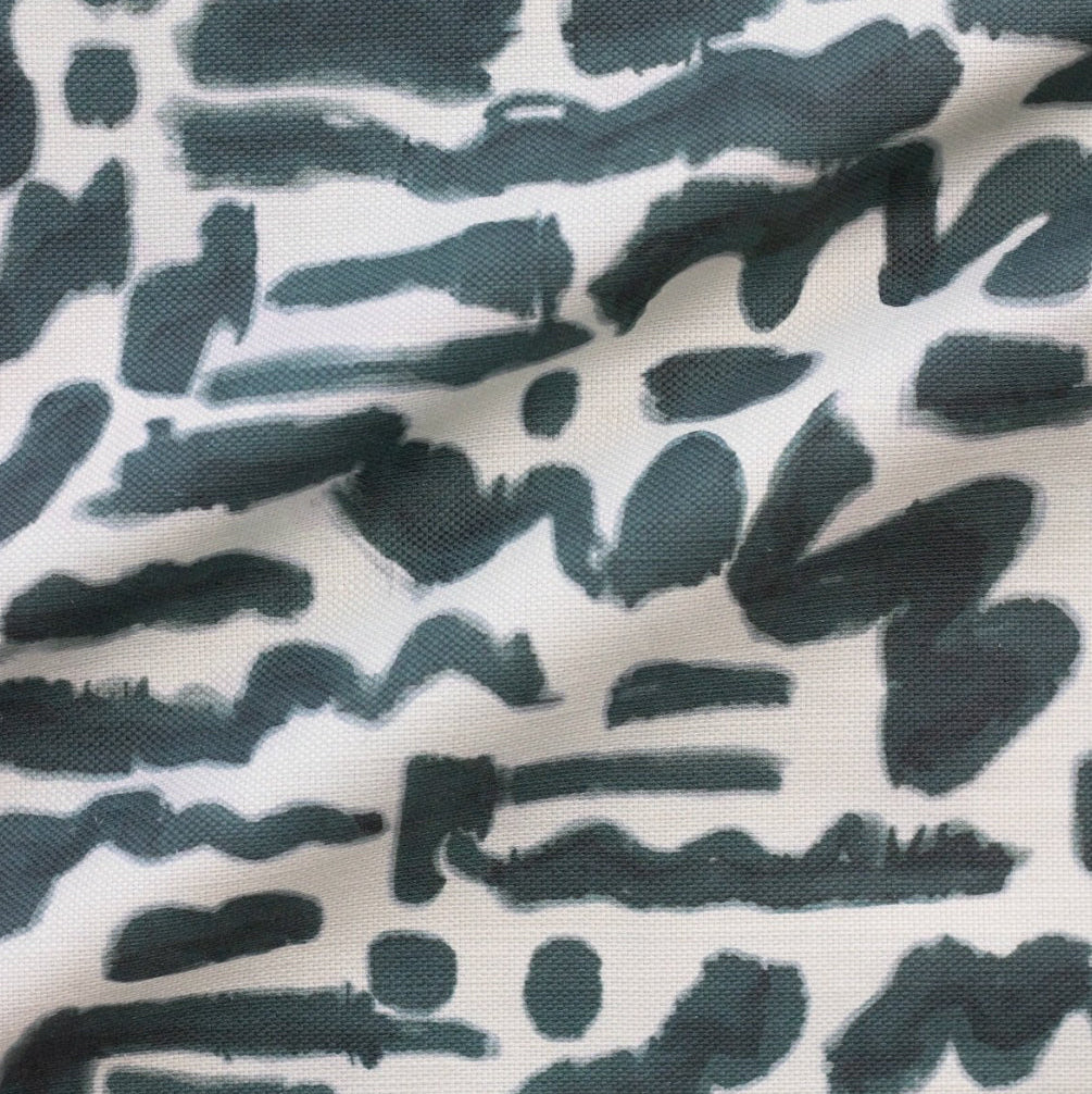A fabric with a geometric pattern featuring what appears to be abstract doodles in dark color strokes on a light background.