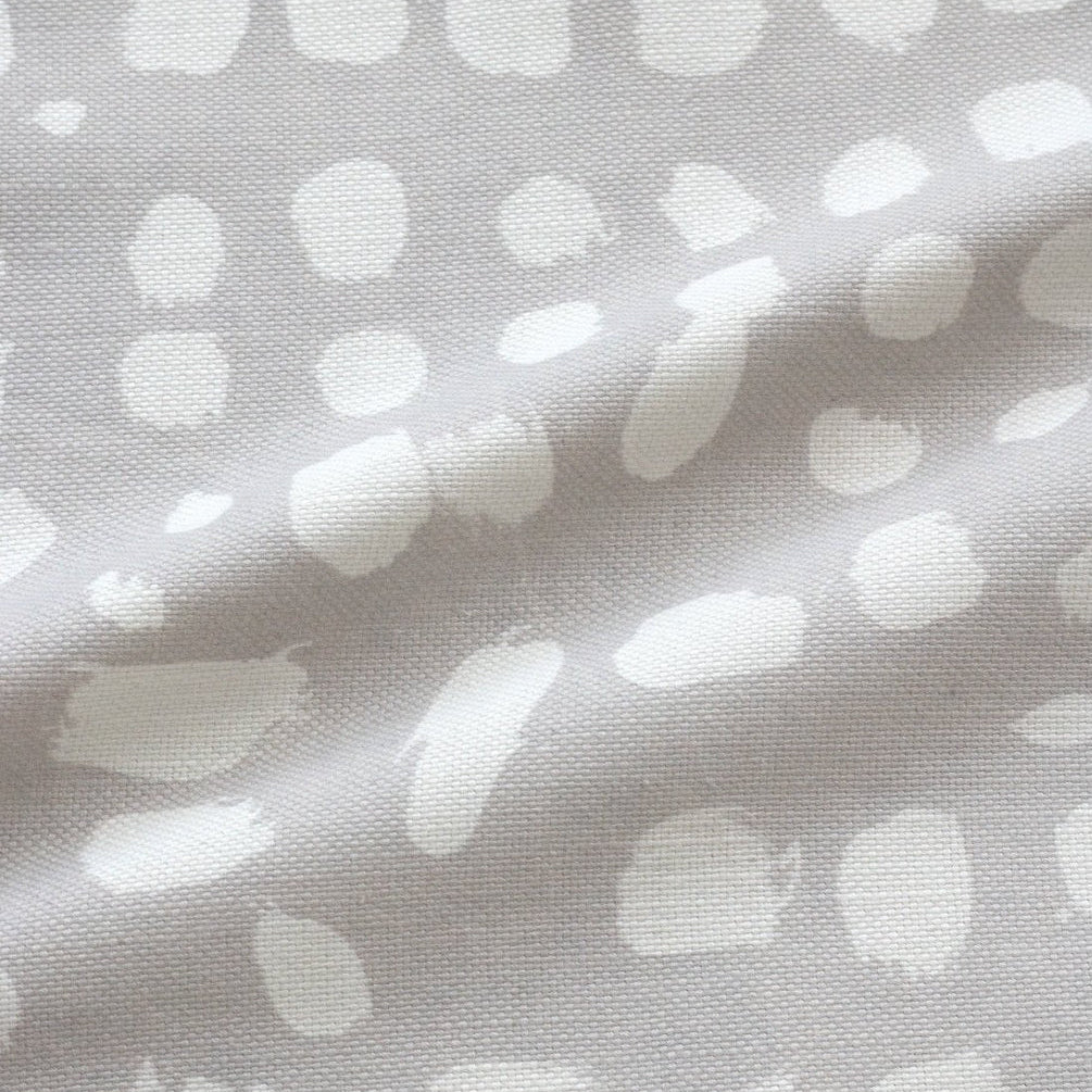 A fabric with a painterly dot design in white on a gray background, showcasing an organic pattern.