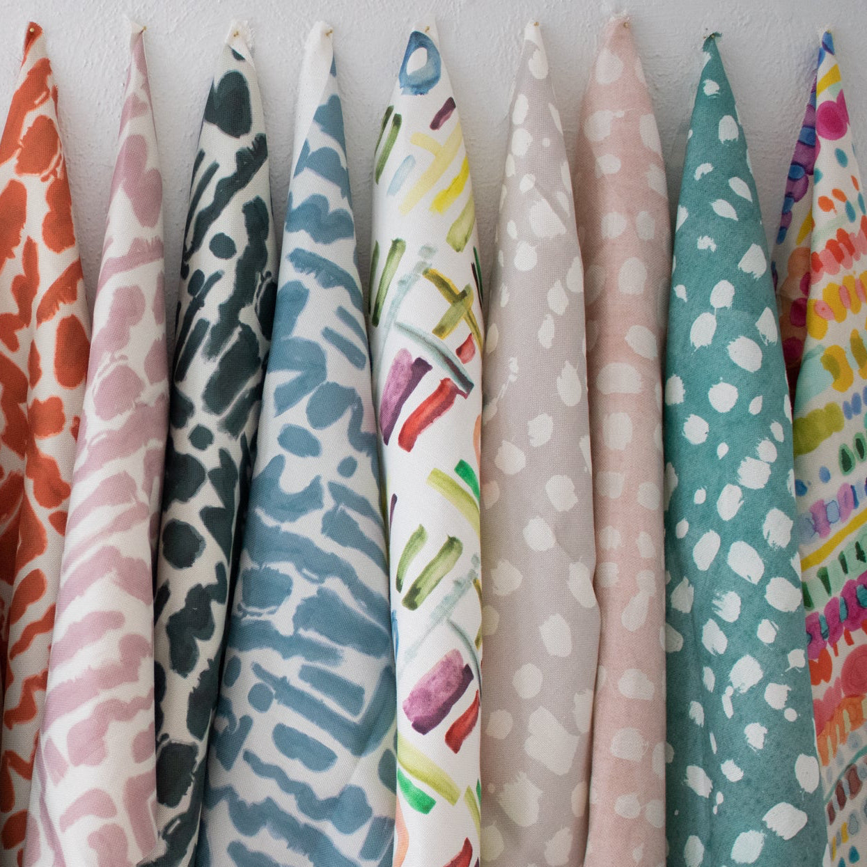 Row of colorful fabric swatches with various patterns on a white background
