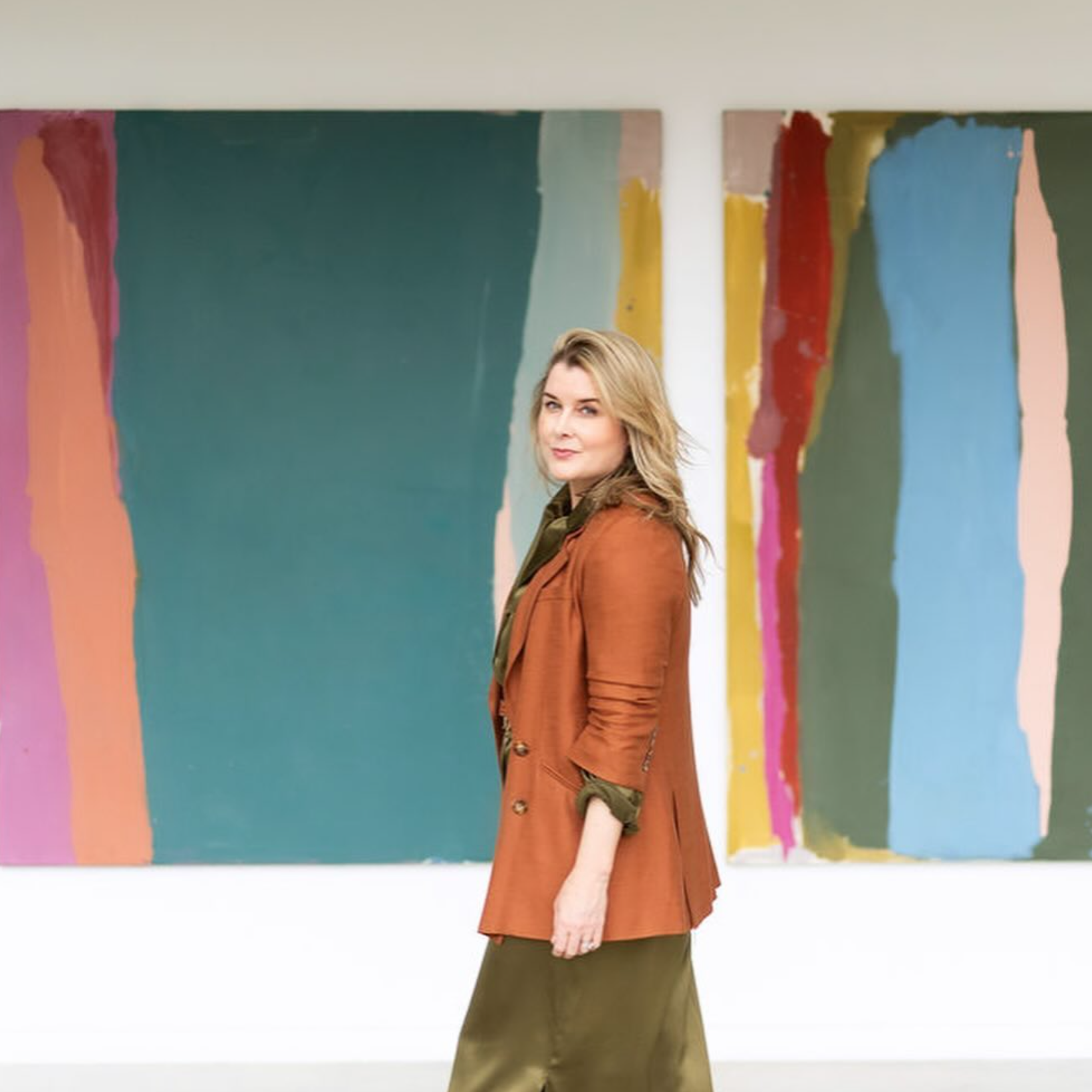 Woman in a brown jacket standing in front of colorful abstract art