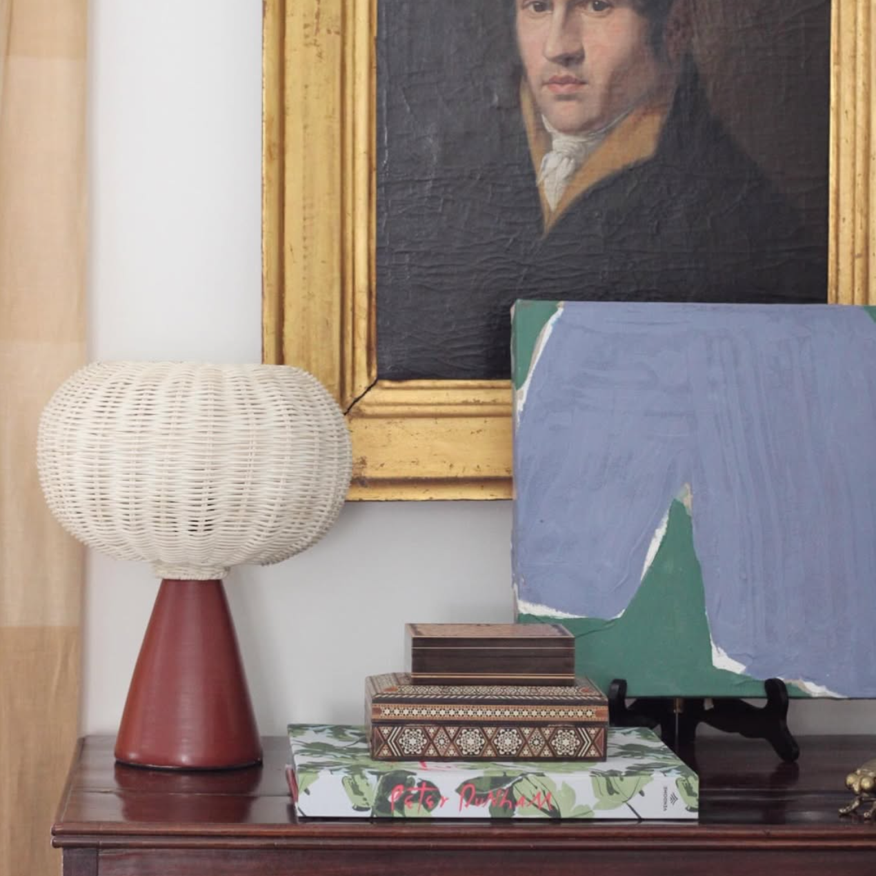 Decorative setup with a lamp, books, and a framed portrait on a wooden surface.