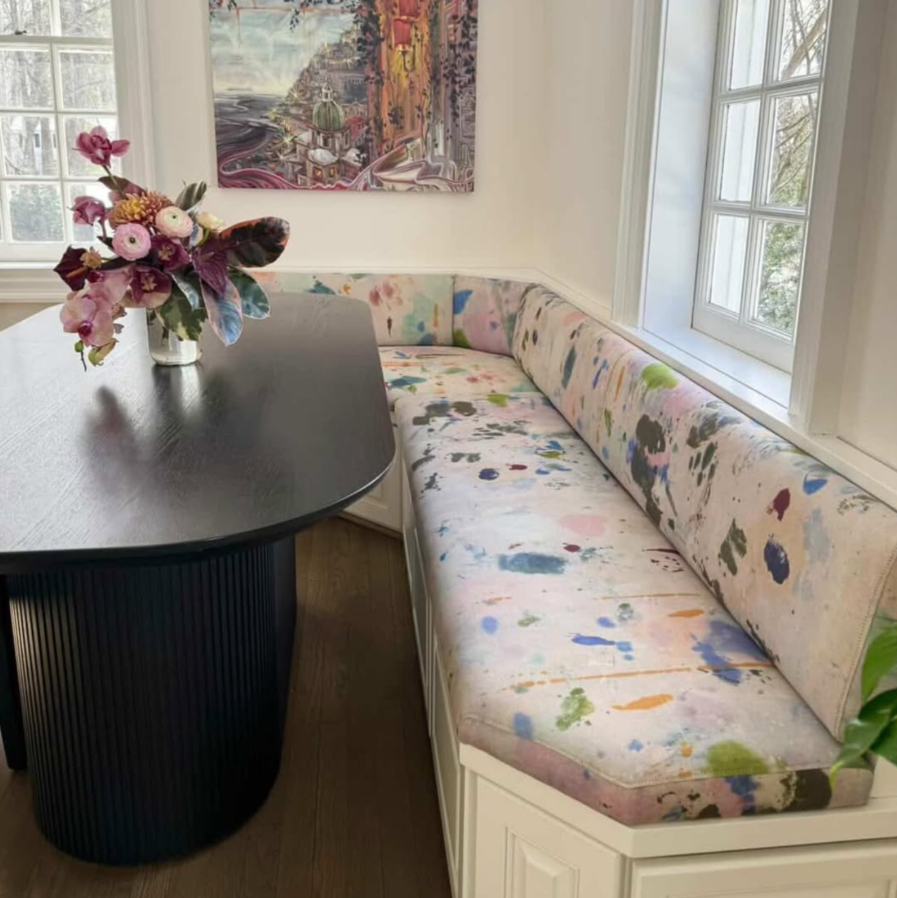 Nook with a floral arrangement, round table, and colorful bench seat.
