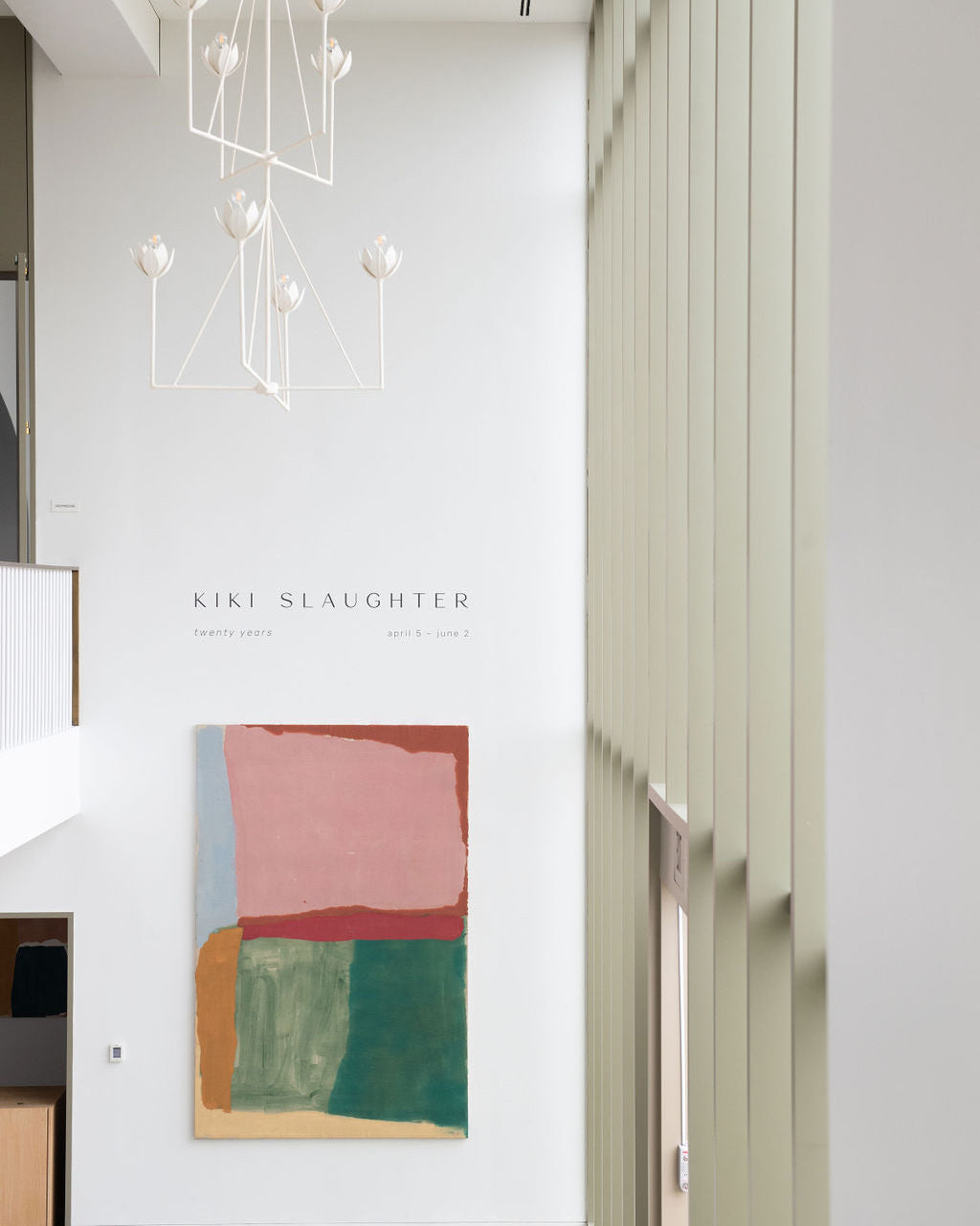 Modern interior with abstract art on a white wall and chandelier.